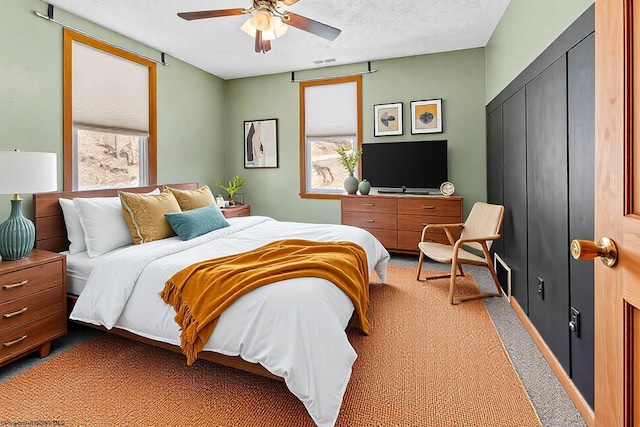 bedroom with visible vents, a ceiling fan, a textured ceiling, a closet, and light colored carpet