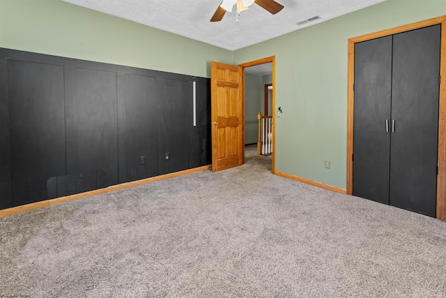 unfurnished bedroom with visible vents, a ceiling fan, a textured ceiling, carpet flooring, and baseboards