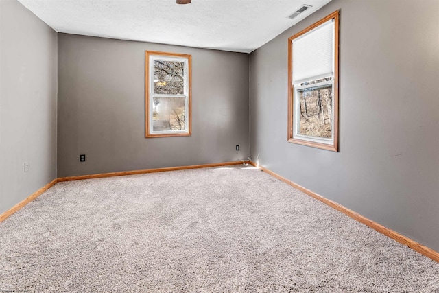 spare room with visible vents, a textured ceiling, baseboards, and carpet