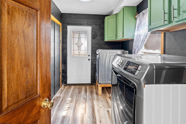 clothes washing area with separate washer and dryer, cabinet space, and light wood finished floors