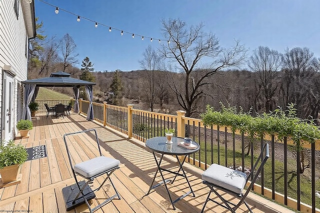 wooden deck with a gazebo and a forest view