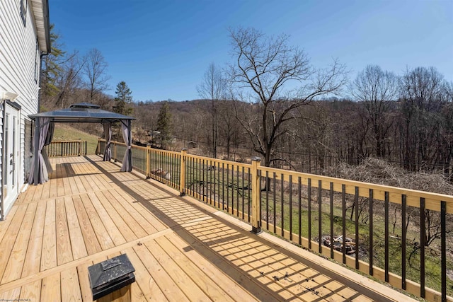 wooden terrace featuring a gazebo and a forest view