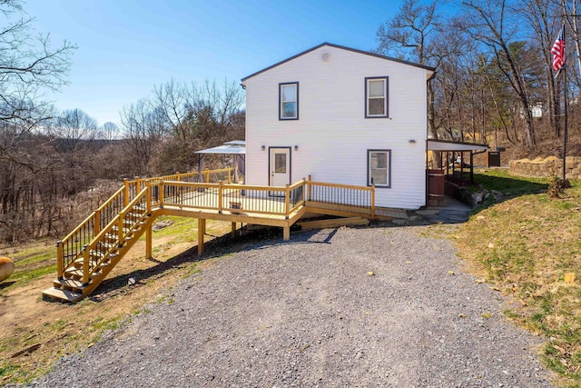 rear view of house featuring a wooden deck and driveway