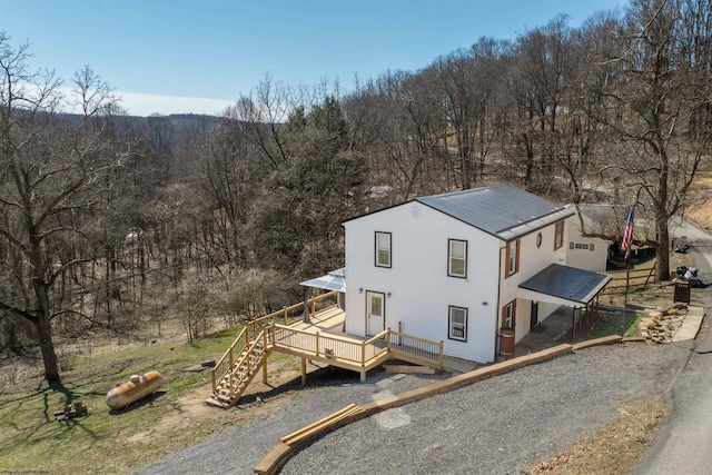 view of front of property with a forest view, a deck, and metal roof