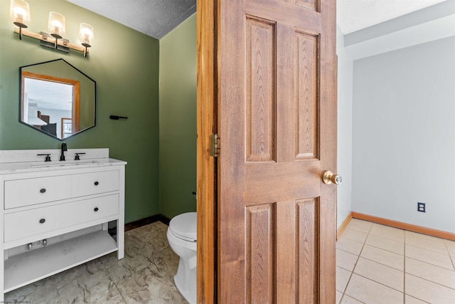 bathroom with vanity, toilet, and baseboards