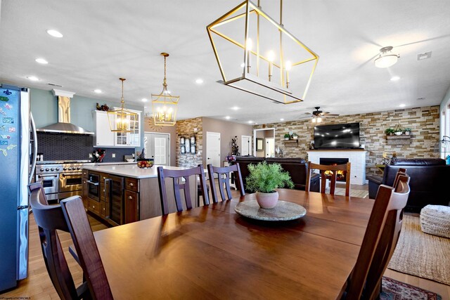 dining space with ceiling fan, wine cooler, light wood-type flooring, a lit fireplace, and recessed lighting