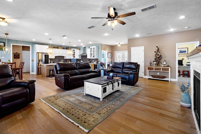 living area with recessed lighting, visible vents, light wood-style flooring, and a fireplace