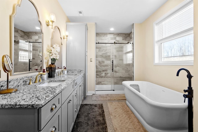 bathroom with double vanity, a shower stall, and a sink