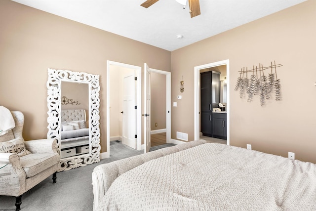 carpeted bedroom with visible vents, baseboards, ensuite bathroom, and ceiling fan