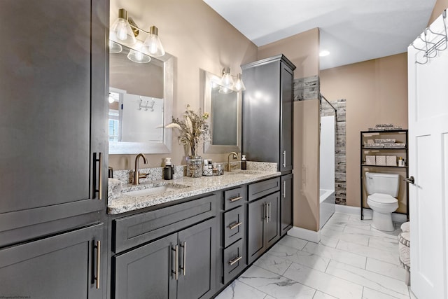 full bath featuring double vanity, marble finish floor, toilet, and a sink