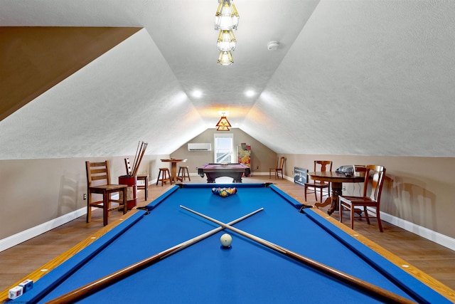 rec room featuring vaulted ceiling, an AC wall unit, baseboards, and wood finished floors