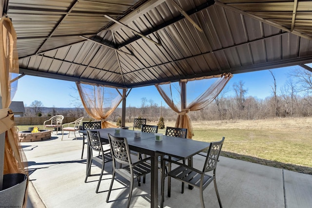 view of patio featuring a gazebo, outdoor dining space, and an outdoor fire pit