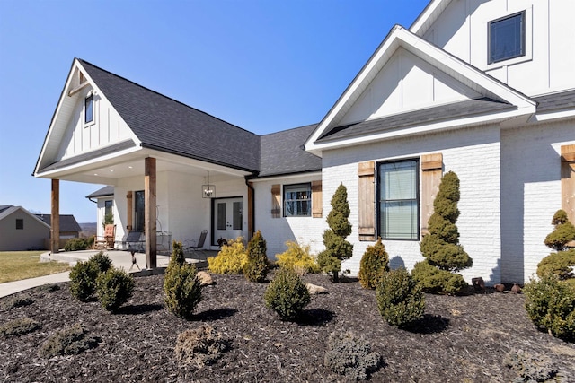 modern farmhouse featuring french doors, brick siding, board and batten siding, and roof with shingles