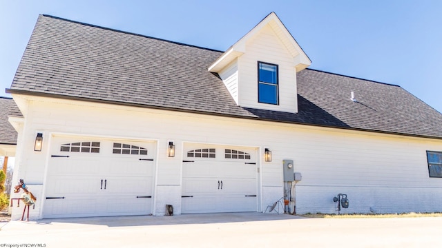 view of home's exterior featuring concrete driveway, a garage, and roof with shingles