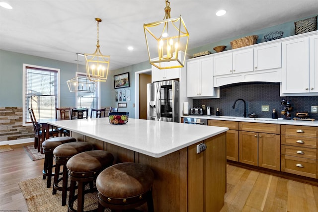 kitchen with a kitchen island, stainless steel fridge with ice dispenser, a sink, light wood-type flooring, and a chandelier