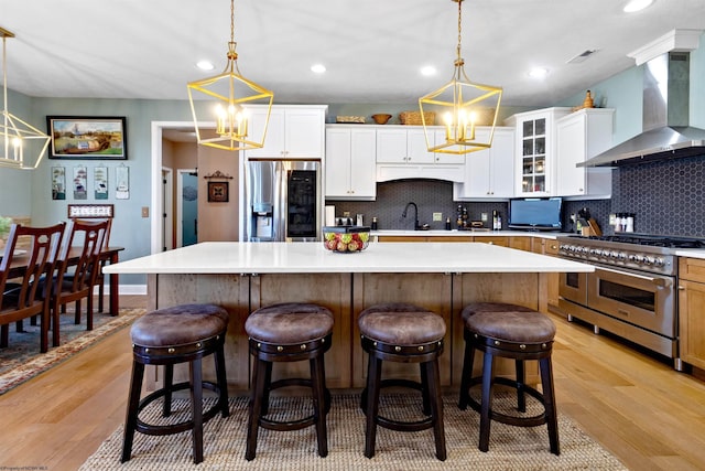 kitchen featuring a sink, stainless steel appliances, wall chimney exhaust hood, and light wood finished floors