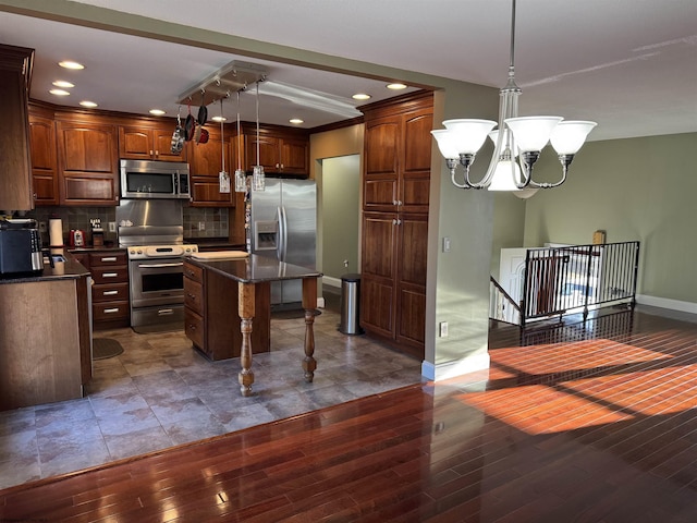 kitchen with dark countertops, decorative backsplash, stainless steel appliances, and a chandelier