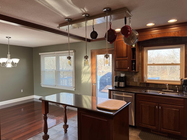 kitchen featuring a sink, backsplash, stainless steel dishwasher, dark countertops, and a textured ceiling