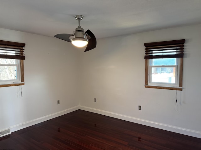 spare room featuring dark wood finished floors, a healthy amount of sunlight, visible vents, and baseboards