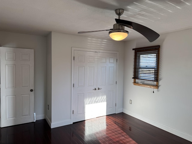 unfurnished bedroom featuring dark wood finished floors, ceiling fan, a textured ceiling, and baseboards