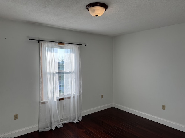 empty room featuring baseboards, a textured ceiling, and dark wood-style flooring