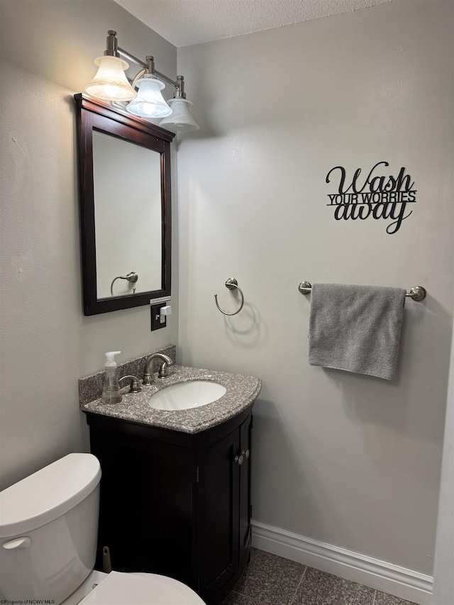 bathroom featuring toilet, vanity, and baseboards