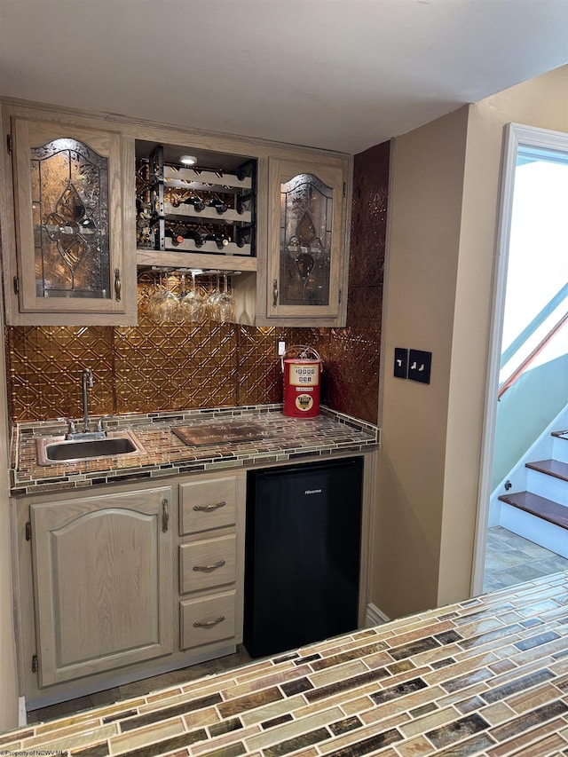 bar featuring indoor wet bar, stairway, backsplash, and a sink