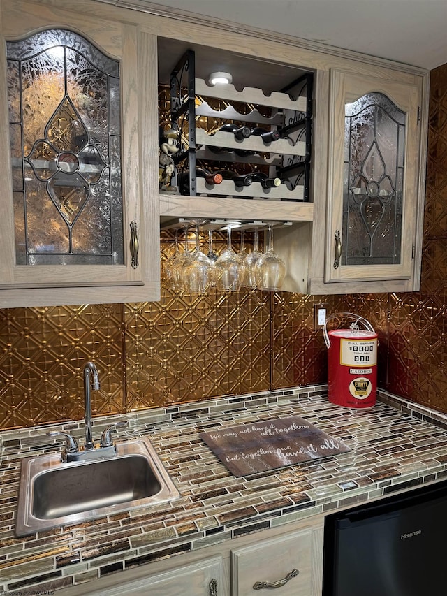 kitchen featuring a sink, glass insert cabinets, backsplash, and tile counters