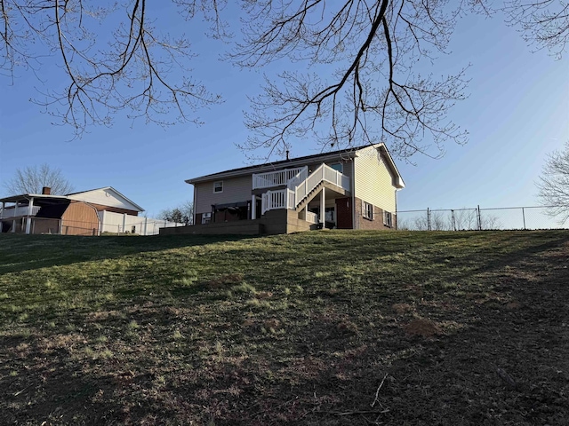 rear view of property featuring brick siding, fence, stairs, a lawn, and a deck