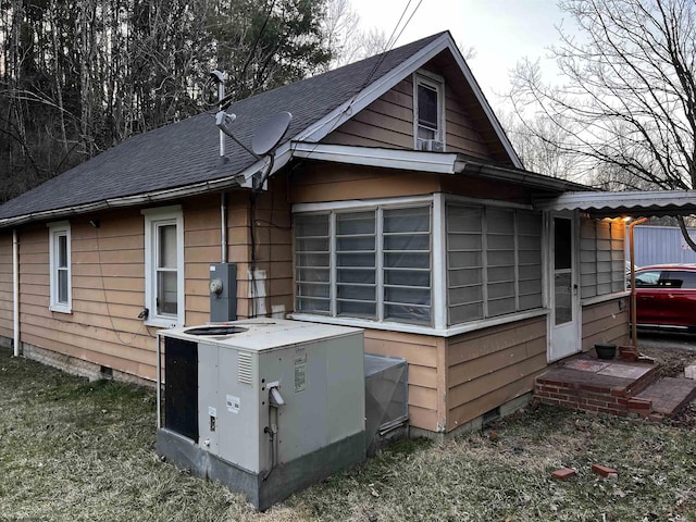 view of side of property featuring crawl space, central air condition unit, and a shingled roof