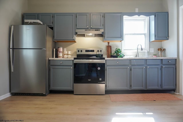 kitchen featuring under cabinet range hood, appliances with stainless steel finishes, a sink, and light countertops