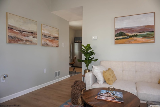 living area featuring visible vents, baseboards, and wood finished floors