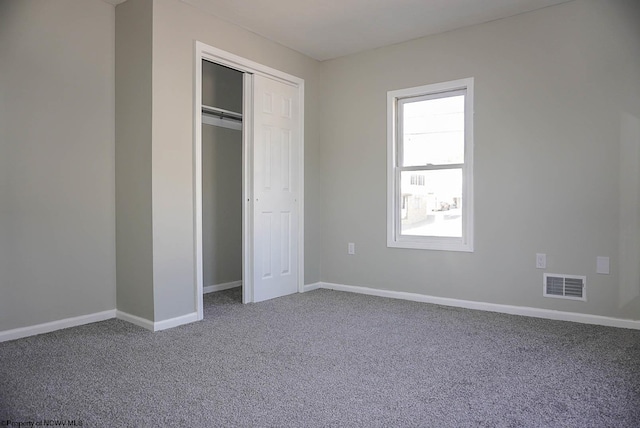 unfurnished bedroom with carpet flooring, baseboards, visible vents, and a closet