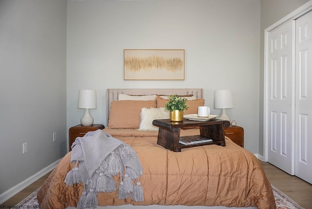 bedroom with wood finished floors, a closet, and baseboards