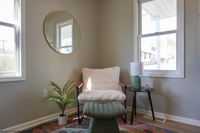 sitting room with visible vents, baseboards, and wood finished floors