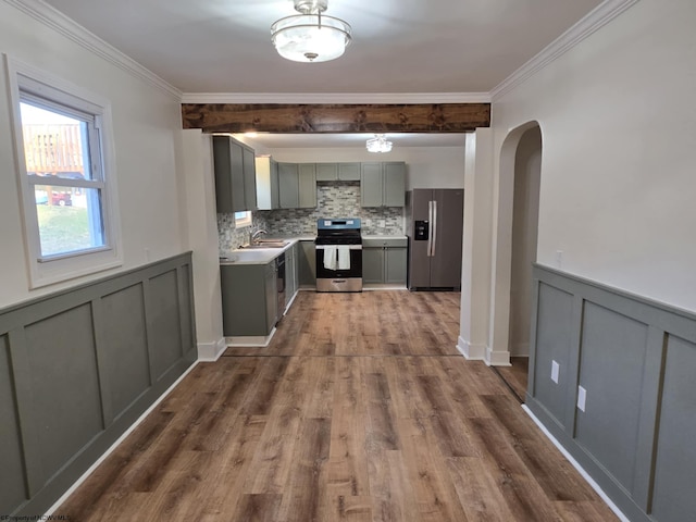 kitchen with a sink, gray cabinetry, arched walkways, and stainless steel appliances