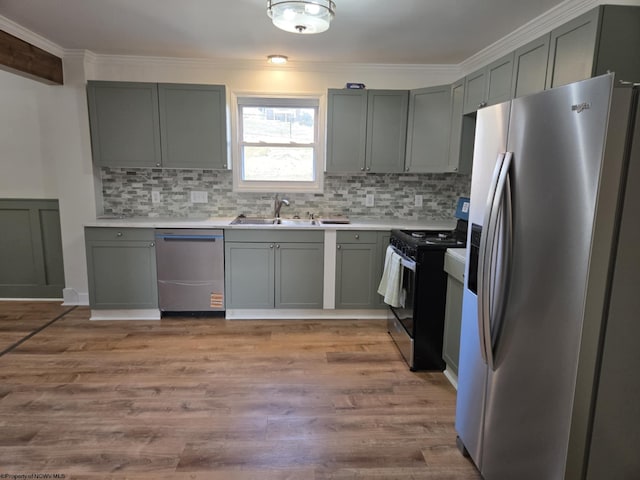 kitchen with tasteful backsplash, light wood-type flooring, light countertops, stainless steel appliances, and a sink