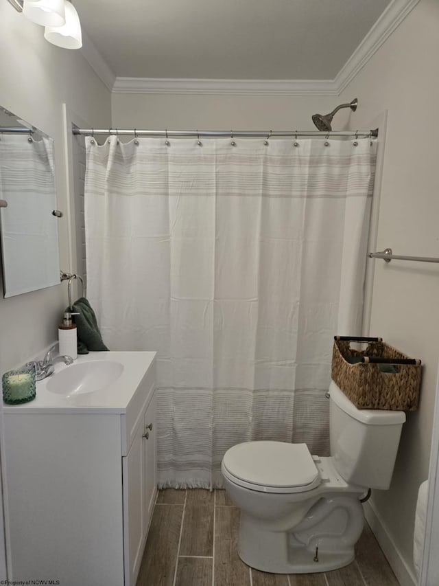 bathroom with vanity, baseboards, wood finish floors, ornamental molding, and toilet