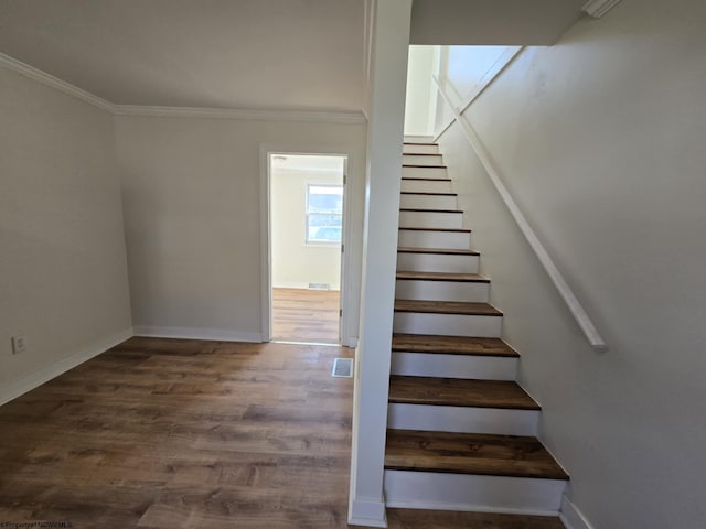 stairs with visible vents, ornamental molding, baseboards, and wood finished floors