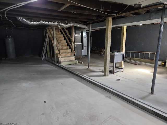 unfinished basement with gas water heater, stairway, and heating unit