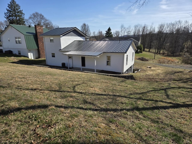 back of house with a patio area, a lawn, a chimney, and metal roof