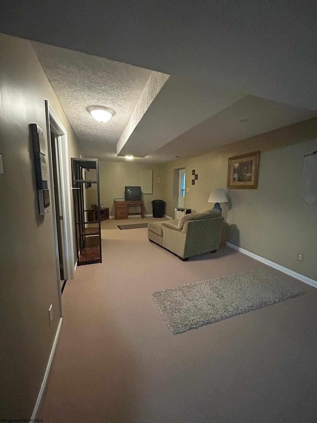 living area with carpet flooring, a textured ceiling, and baseboards