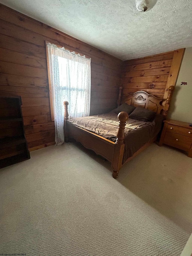 bedroom with light carpet, a textured ceiling, and wood walls