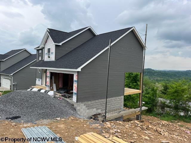 view of side of property with an attached garage and a shingled roof