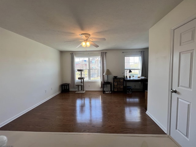 unfurnished room featuring a ceiling fan, wood finished floors, baseboards, and a textured ceiling