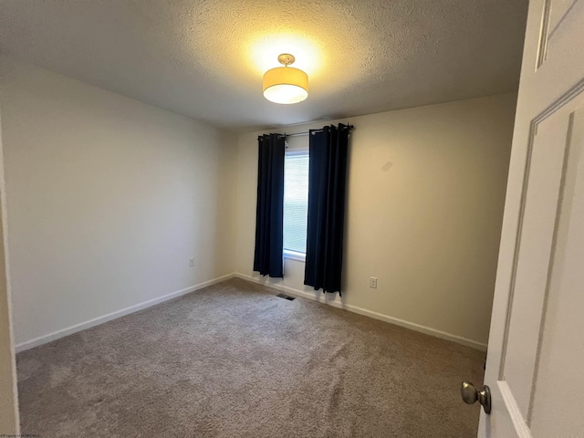 carpeted spare room with visible vents, baseboards, and a textured ceiling