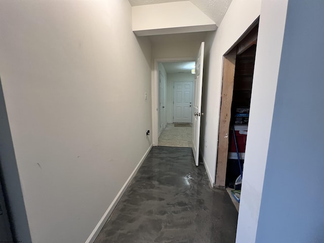 corridor featuring baseboards and concrete floors