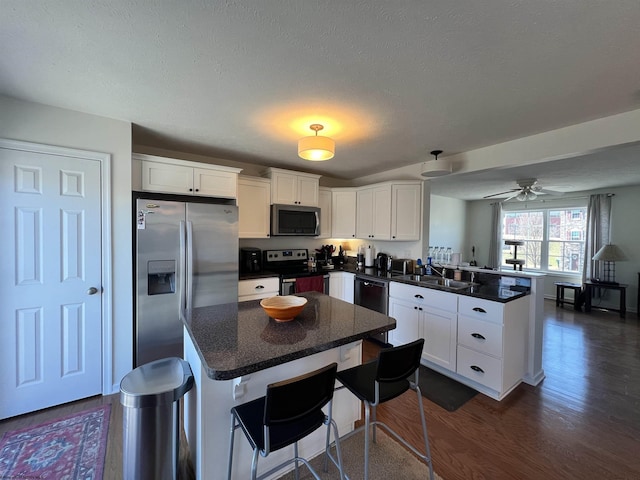 kitchen with a center island, white cabinetry, a peninsula, and stainless steel appliances