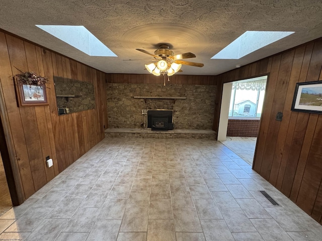 living area with wooden walls, a ceiling fan, visible vents, and a textured ceiling