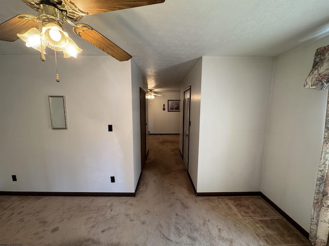 interior space with a ceiling fan, baseboards, a textured ceiling, and carpet flooring